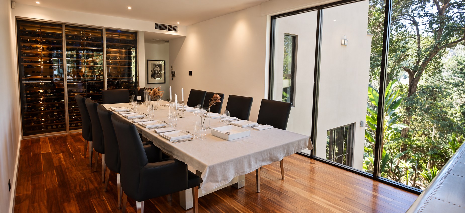 Formal dining space with a long table and bushland outlook