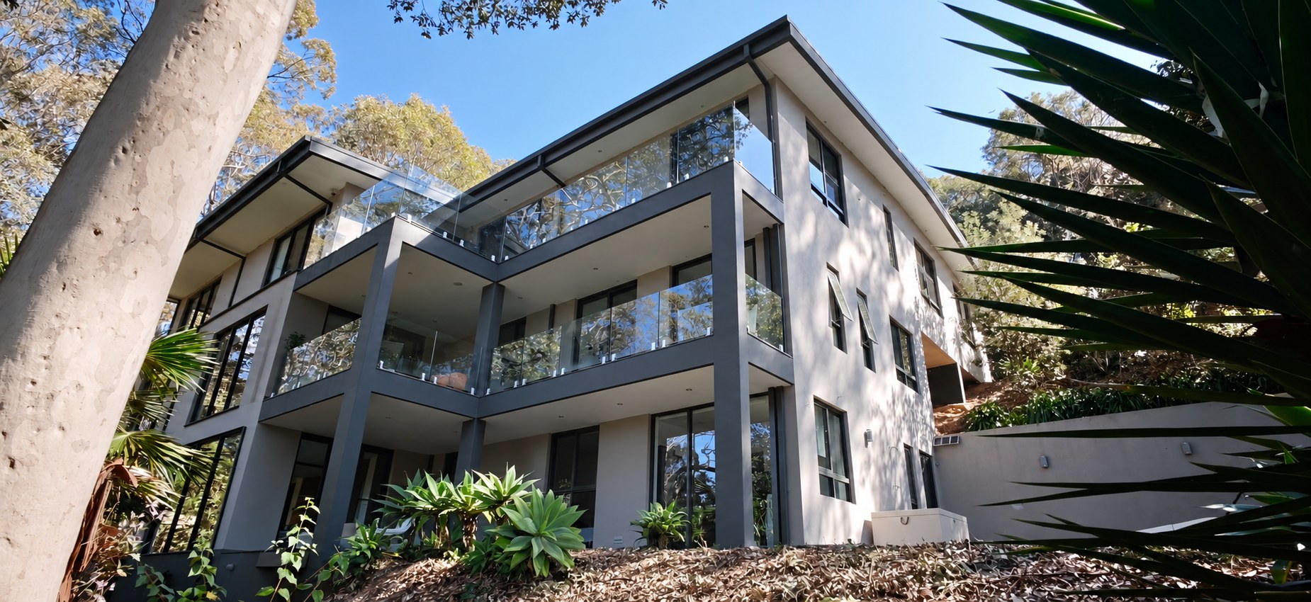 The three-level residence framed by mature bushland in daylight