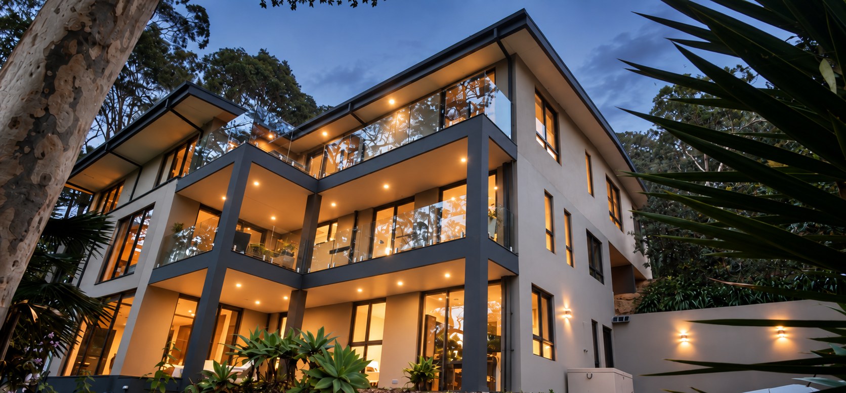 The three-level residence illuminated at twilight among mature bushland